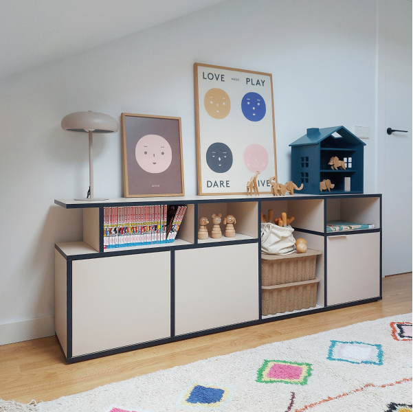 A contrast edge Type02 Sideboard in Sand + Midnight Blue with mixed open and closed storage sections stands in a kid's room with colorful posters resting on top and toys tucked neatly away inside. 